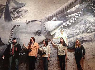 students posing in front of large photo of a shark